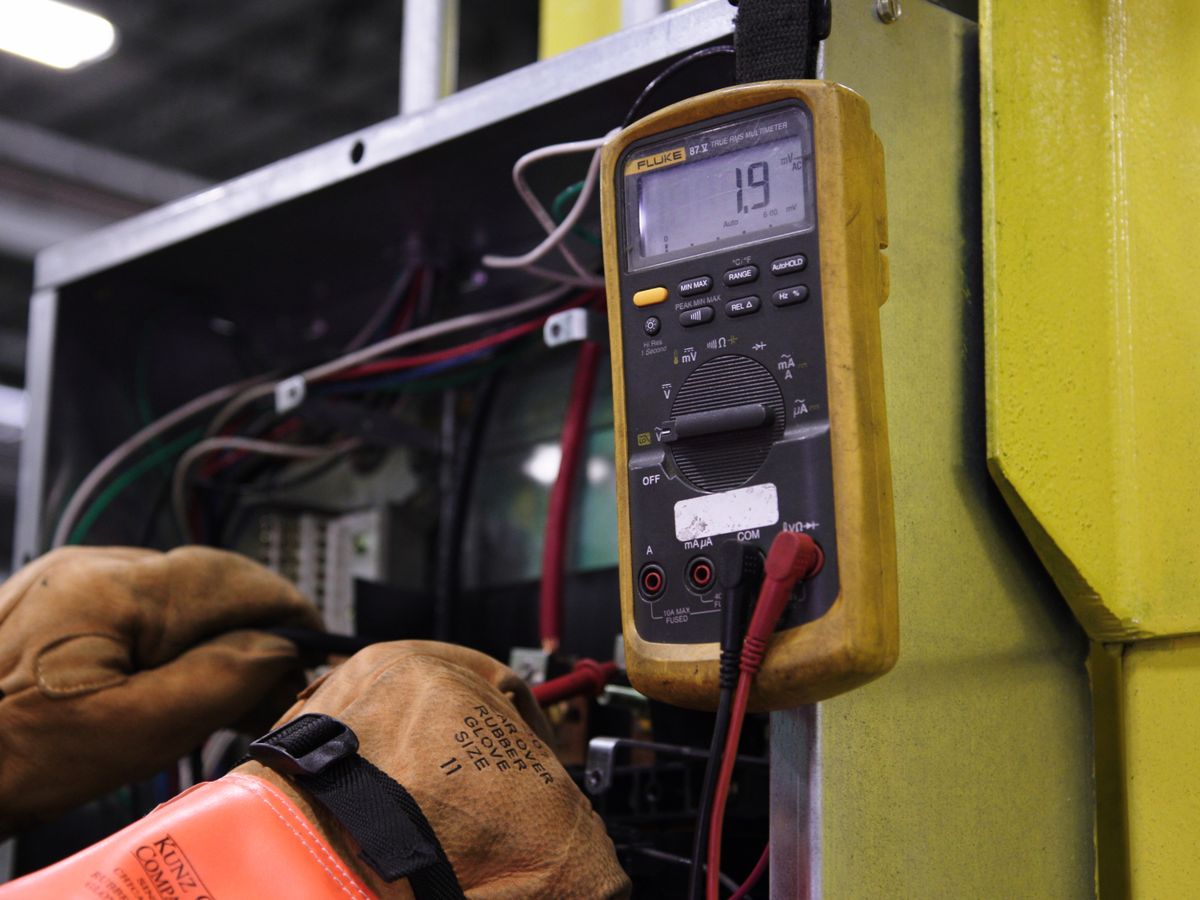 Arcwell electrician using a multimeter to diagnose an electrical fault