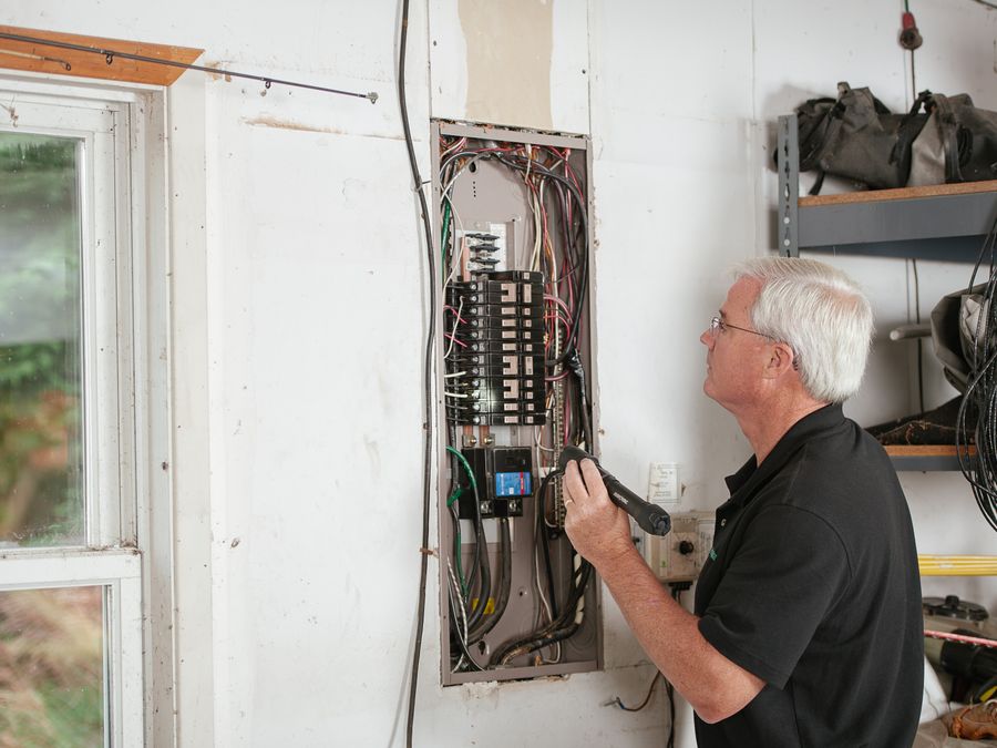 Electrician inspecting a residential fuse box for a pre-sale safety report